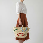 Woven Straw Market Tote Bag with Embroidered Winking Face Design